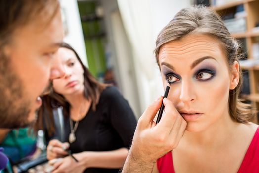 Close up of a make-up man artist getting eyeliner to model.