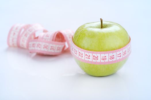 Green apple with a measuring tape around it