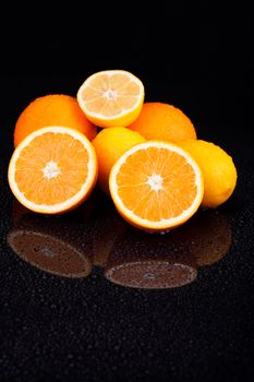 Juicy delicious sliced oranges and lemons on wet table