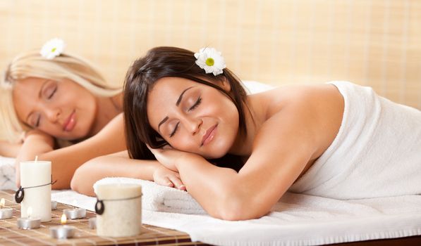 Two young beautiful women relaxing and enjoying at the spa center