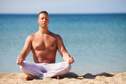 Young man meditating on the beach