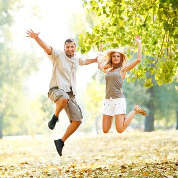 Beautiful happy couple jamping in the park 