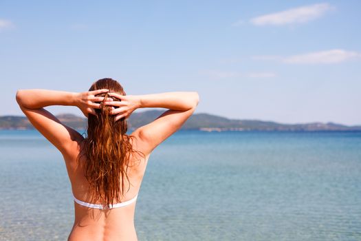 young woman on the beach with hands in hair
