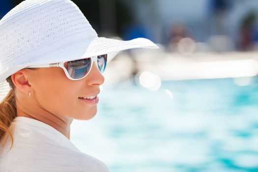 Young beautiful woman enjoying the sun by the pool