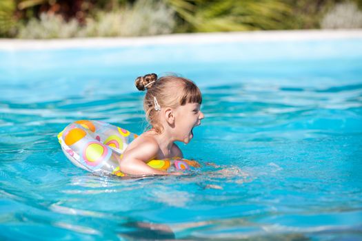 Happy little girl swimming in the pool with Swimming Tube 