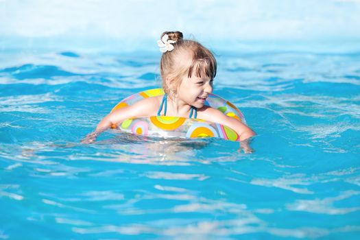 Happy little girl swimming in the pool with Swimming Tube 