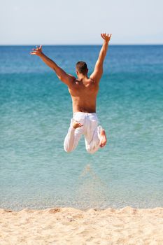 Happy young man in white pants jumping into water