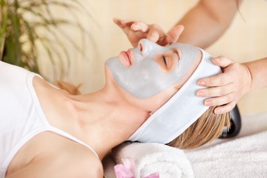 Young beautiful woman receiving cosmetic facial mask in spa beauty salon