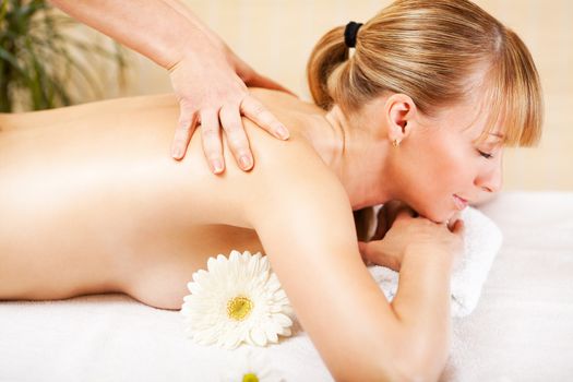 Young beautiful woman receiving back massage at the spa center
