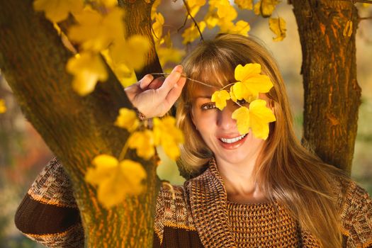 Beautiful women are hidden behind the leaves in autumn