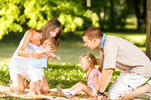 Baby boy makes first steps with his family in beautiful nature