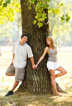 Couple in love holding hands leaning against a tree