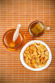 Fresh honey, tea and breakfast flakes, top view