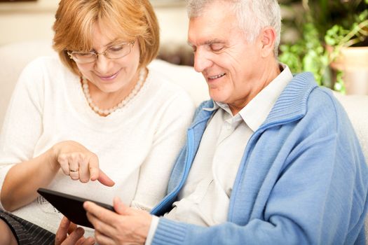 Happy senior couple using tablet at home