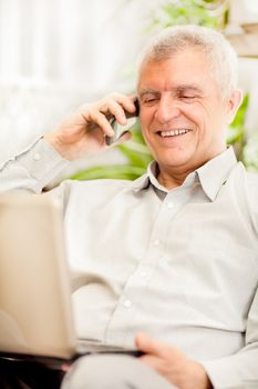 Happy senior businessman working at home on laptop
