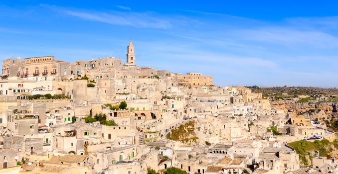 panoramic view of typical stones (Sassi di Matera) and church of Matera under blue sky. Basilicata, Italy