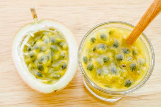 natural passion fruit juice in glass with wooden spoon on wooden table.