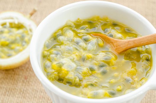 Passion fruit juice white bowl with wooden spoon on sack background.