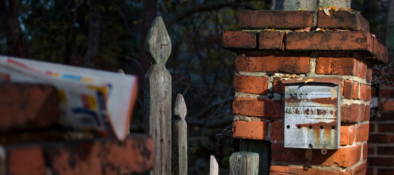 Very old rusty post box on the brick column.