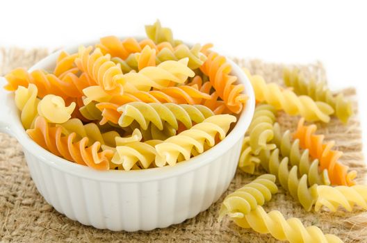 dried italian pasta (macaroni) in white bowl on sack background.