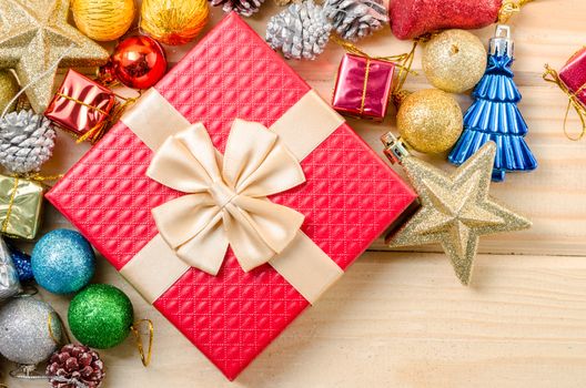 Red gift box and christmas decorations on wooden background.