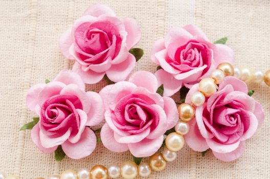 Pink rose with pearls on fabric background.