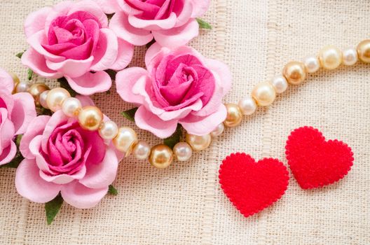 Red heart and pink rose on fabric background. Love of time concept.