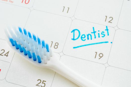 The words Dentist written on a calendar to remind you an important appointment with tooth brush.