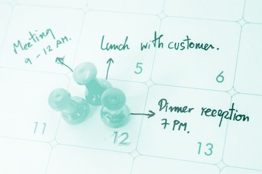 Pushpin on calendar with busy day overworked schedule.