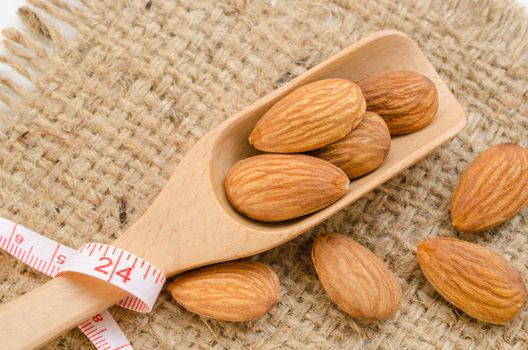 Almond and measuring meter on sack background. Diet concept.