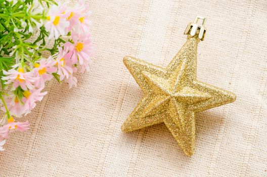 Gold five pointed star christmas decoration with flower on fabric background.