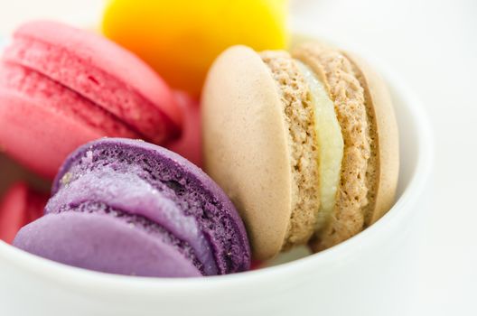 Colorful sweet macaroons in a ceramic cup isolated on a white background