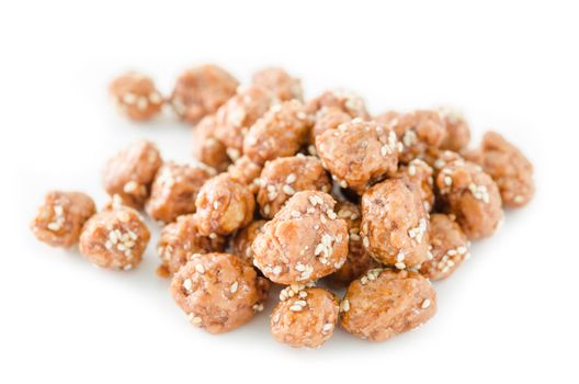 Honey roasted coated peanuts and white sesame seeds on white background.