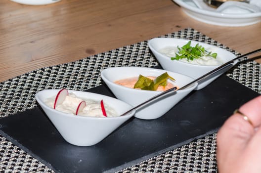 Three yoghurt dips, sauces with radishes, peppers and herbs.