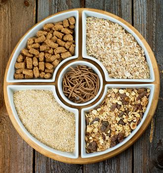 Various Oat Flakes, Muesli and Bran in White Bowls closeup on Rustic Wooden background. Top View