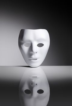 White blank plastic mask on reflective surface.