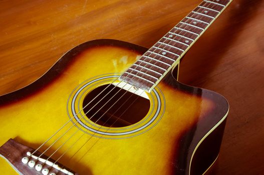 Acoustic guitar on wood background.