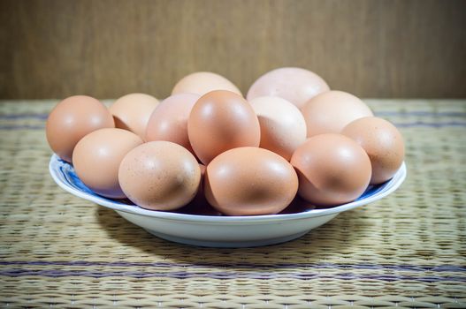 Chicken eggs in a dish on wood background.