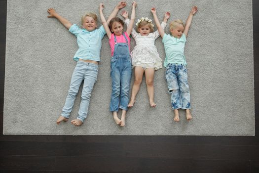 Group of happy kids laying on floor, top view