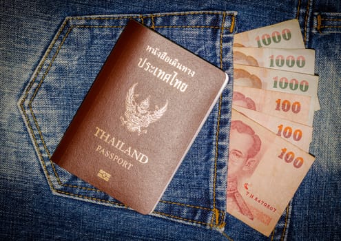 Close up blue jeans pocket with Thailand passport and thai money.
