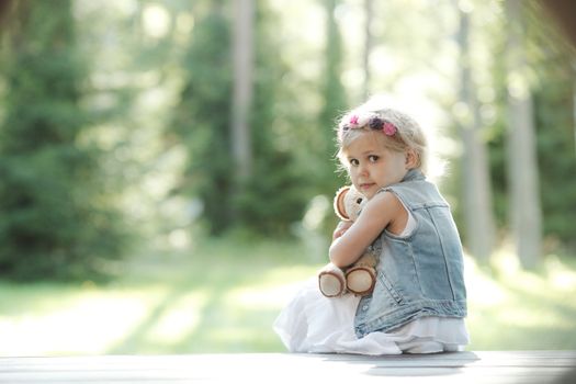 Pretty girl playing with teddy bear outdoors