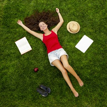 Beautiful and happy young woman lying on the grass