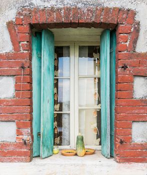 Window of a farmhouse with wooden balconies and red brick frame.