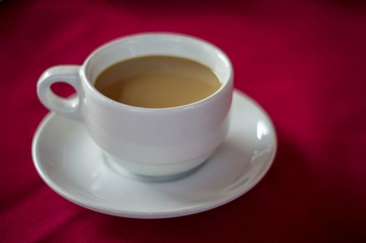 Coffee cup on red tablecloth.