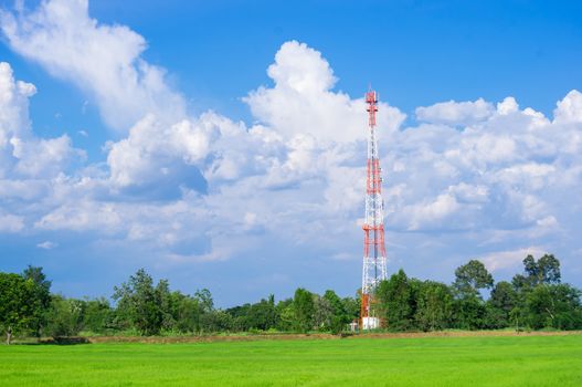 Telecommunication Radio Antenna and Satelite Tower with blue sky with cloud and green field.