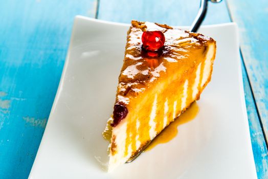 A pice of pineapple cake with caramel on white plate and blue wood table