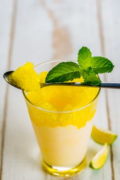 Lemon refreshing dessert in glass decorated with lemon and mint on white wood table