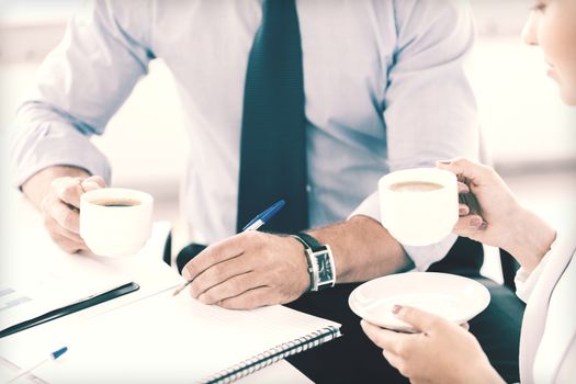 business, school and education concept - smiling businesswoman and businessman discussing something in office