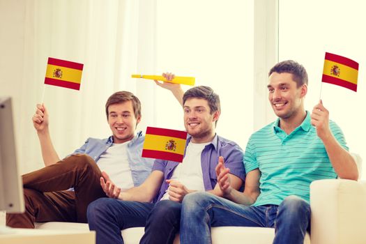 friendship, sports and entertainment concept - happy male friends with flags and vuvuzela supporting football team at home