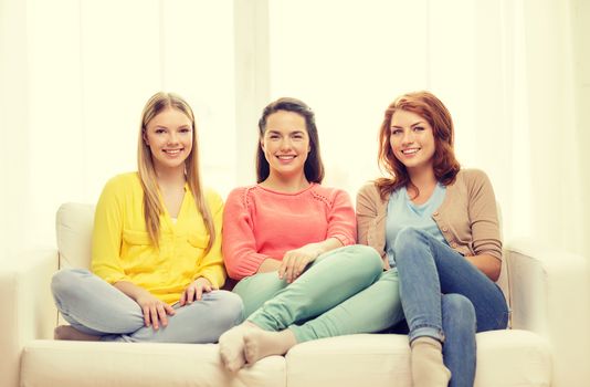 friendship and happiness concept - three girlfriends having a talk at home